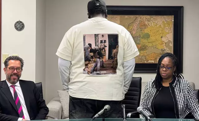 Garrison Gibson, a Liberian man who has lived in the U.S. for around three decades, shows a photo of his arrest on a t-shirt as he speaks with reporters during a news conference Saturday, Jan. 17, 2026. (AP Photo/Jack Brook)
