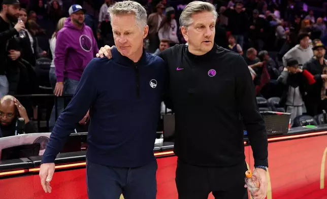 Golden State Warriors head coach Steve Kerr, left, and Minnesota Timberwolves head coach Chris Finch, right, talk after an NBA basketball game Sunday, Jan. 25, 2026, in Minneapolis. (AP Photo/Matt Krohn)