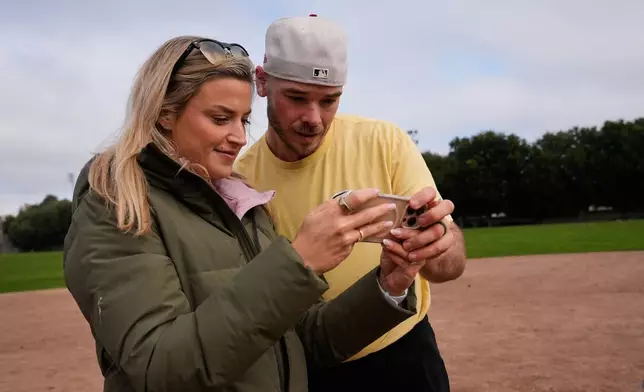 Daulton Jefferies, right, and his wife Natalie watch a video of him throwing a pitch while working out at Heather Farms Park in Walnut Creek, Calif., Saturday, Dec. 13, 2025. (AP Photo/Godofredo A. Vásquez)