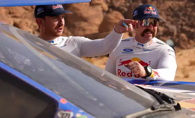 Driver Mitch Guthrie, left, and co-driver Kellon Walch talk after the fourth stage of the Dakar Rally between Alula and Hail, Saudi Arabia, Wednesday, Jan. 7, 2026. (AP Photo/Thibault Camus)