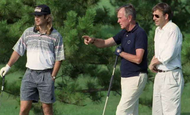 FILE - President George H.W. Bush talks with tennis star Andre Agassi, left, and actor Kevin Costner, right, while playing the 18th hole at Andrews Air Force Base, Md., July 28, 1991. (AP Photo/Doug Mills, File)