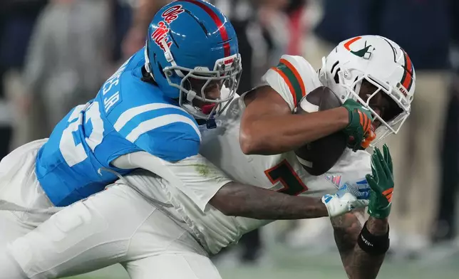 Miami wide receiver CJ Daniels (7) catches a pass while tackled by Mississippi cornerback Chris Graves Jr. (32) during the first half of the Fiesta Bowl NCAA college football playoff semifinal game, Thursday, Jan. 8, 2026, in Glendale, Ariz. (AP Photo/Ross D. Franklin)