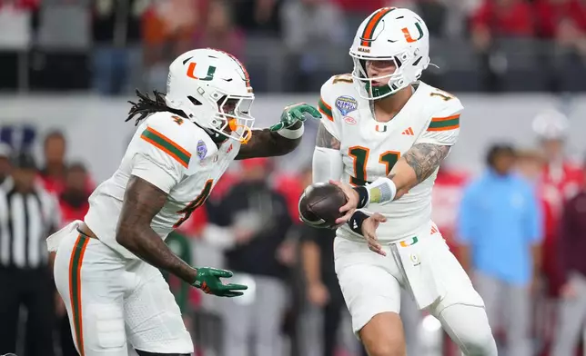 Miami quarterback Carson Beck, right, prepares to hand off to running back Mark Fletcher Jr. during the first half of the Cotton Bowl College Football Playoff quarterfinal game against Ohio State Wednesday, Dec. 31, 2025, in Arlington, Texas. (AP Photo/Julio Cortez)
