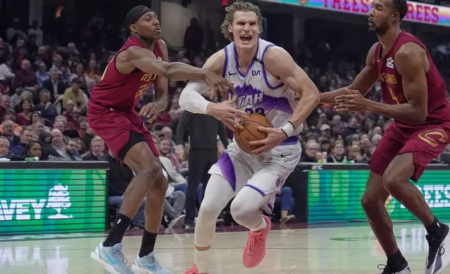 Utah Jazz forward Lauri Markkanen, center, drives between Cleveland Cavaliers forward Nae'qwan Tomlin, left, and center Evan Mobley, right, in the first half of an NBA basketball game in Cleveland, Monday, Jan. 12, 2026. (AP Photo/Sue Ogrocki)