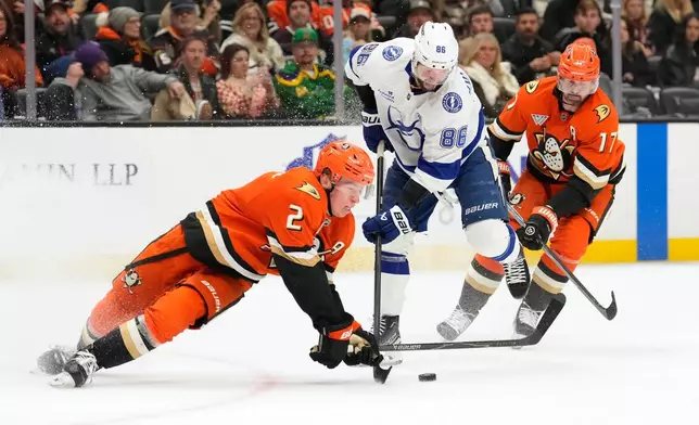 Anaheim Ducks defenseman Jackson Lacombe, left, falls as he tries to pass the puck while under pressure from Tampa Bay Lightning right wing Nikita Kucherov, center as left wing Alex Killorn skates behind during the second period of an NHL hockey game Wednesday, Dec. 31, 2025, in Anaheim, Calif. (AP Photo/Mark J. Terrill)