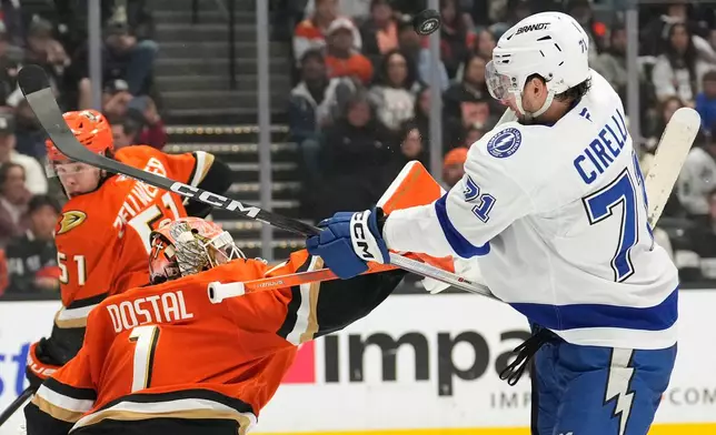 Anaheim Ducks goaltender Lukas Dostal, center, deflects a shot as Tampa Bay Lightning center Anthony Cirelli, right, swings at it during the second period of an NHL hockey game Wednesday, Dec. 31, 2025, in Anaheim, Calif. (AP Photo/Mark J. Terrill)