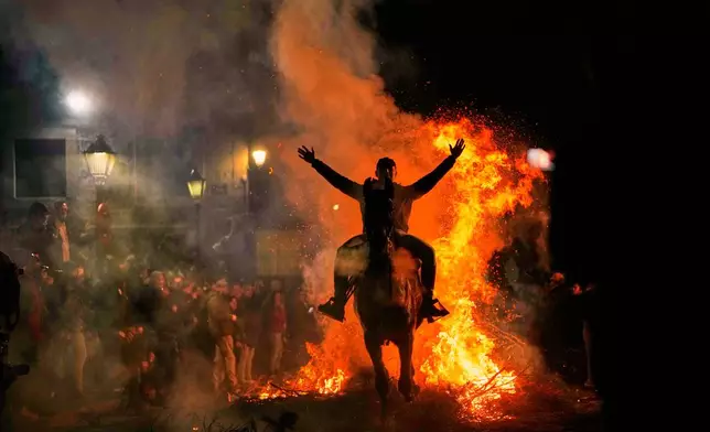 A man rides a horse through a bonfire as part of a ritual in honor of Saint Anthony the Abbot, the patron saint of domestic animals, in San Bartolome de Pinares, Spain, Friday, Jan. 16, 2026. (AP Photo/Manu Fernandez)
