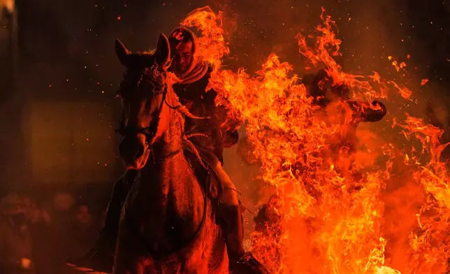 A man rides a horse through a bonfire as part of a ritual in honor of Saint Anthony the Abbot, the patron saint of domestic animals, in San Bartolome de Pinares, Spain, Friday, Jan. 16, 2026. (AP Photo/Manu Fernandez)