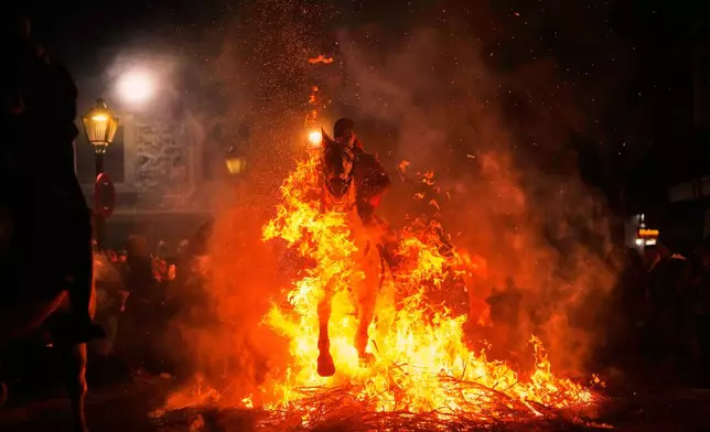 A man rides a horse through a bonfire as part of a ritual in honor of Saint Anthony the Abbot, the patron saint of domestic animals, in San Bartolome de Pinares, Spain, Friday, Jan. 16, 2026. (AP Photo/Manu Fernandez)