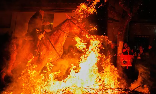 A man rides a horse through a bonfire as part of a ritual in honor of Saint Anthony the Abbot, the patron saint of domestic animals, in San Bartolome de Pinares, Spain, Friday, Jan. 16, 2026. (AP Photo/Manu Fernandez)