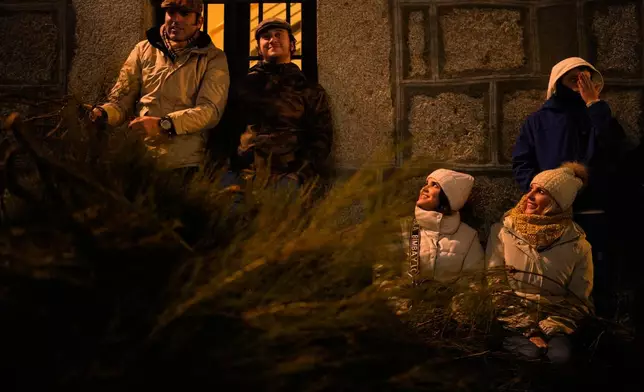 Attendees wait next to the bushes that will be set alight as part of a ritual in honor of Saint Anthony the Abbot, the patron saint of domestic animals, in San Bartolome de Pinares, Spain, Friday, Jan. 16, 2026. (AP Photo/Manu Fernandez)