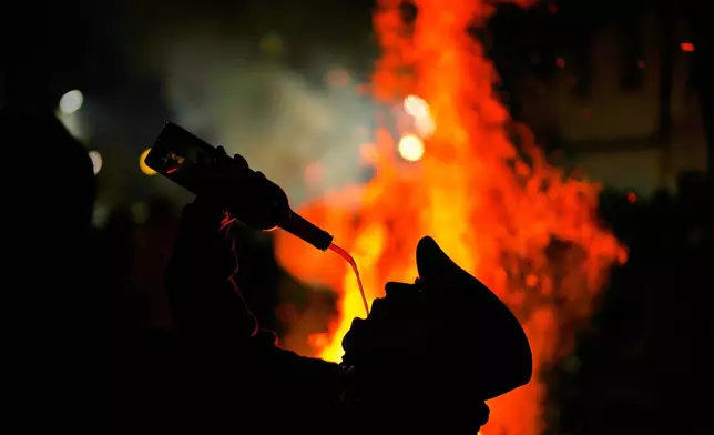An assistant drinks wine from a bottle during a ritual in honor of Saint Anthony the Abbot, the patron saint of domestic animals, in San Bartolome de Pinares, Spain, Friday, Jan. 16, 2026. (AP Photo/Manu Fernandez)