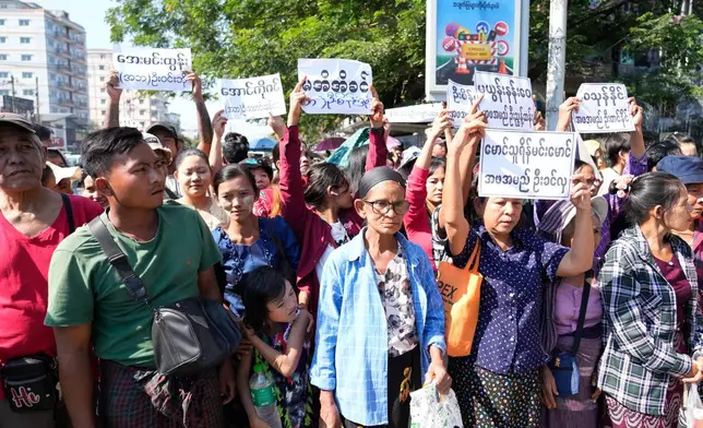 Family members and colleagues holding nameplates wait to welcome the released prisoners from Insein Prison Sunday, Jan. 4, 2026, in Yangon, Myanmar. (AP Photo/Thein Zaw)