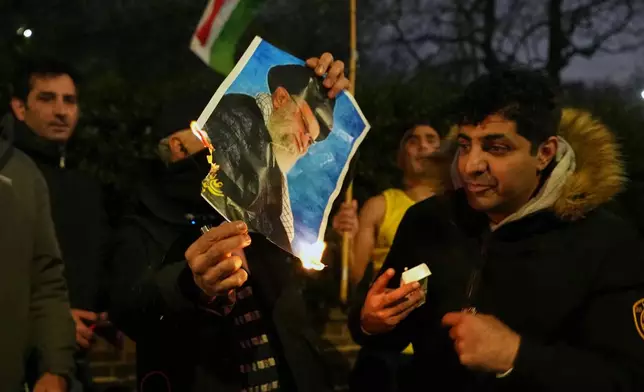 A picture of Ayatollah Ali Khamenei is set alight by protesters outside the Iranian Embassy in London, Monday, Jan. 12, 2026. (AP Photo/Alastair Grant)