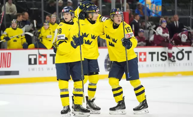 Sweden defenseman Sascha Boumedienne, center, celebrates with forwards Victor Eklund, left, and Sweden Ivar Stenberg, right, after scoring a goal during the second period of an IIHF World Junior Hockey championship quarterfinal game against Latvia, Friday, Jan. 2, 2026, in St. Paul, Minn. (AP Photo/Abbie Parr)