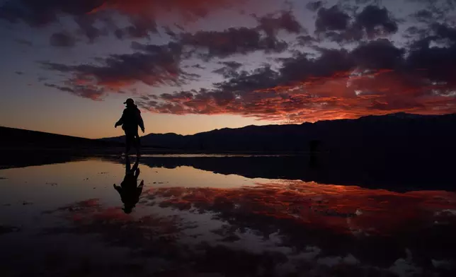 A person wades in Lake Manly, an ephemeral lake in Badwater Basin at Death Valley National Park, Friday, Jan. 23, 2026, in California. (AP Photo/John Locher)