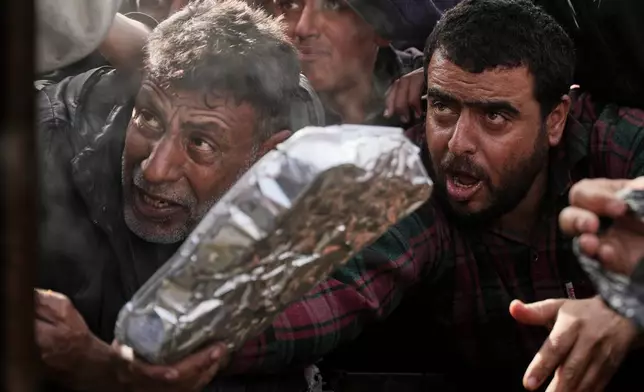 Palestinians wait to receive donated food at a distribution center in Khan Younis, southern Gaza Strip, Friday, Jan 23, 2026. (AP Photo/Abdel Kareem Hana)