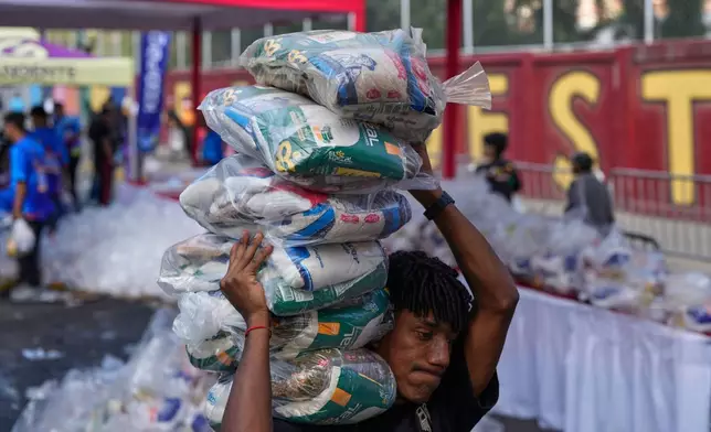 A worker carries bags of food at a government-subsidized market in Caracas, Venezuela, Sunday, Jan. 25, 2026. (AP Photo/Ariana Cubillos)