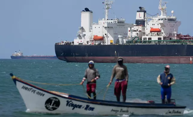 Fishermen pass an oil tanker in the Gulf of Venezuela off the shore of Punta Cardon, Venezuela, Wednesday, Jan. 14, 2026. (AP Photo/Matias Delacroix)