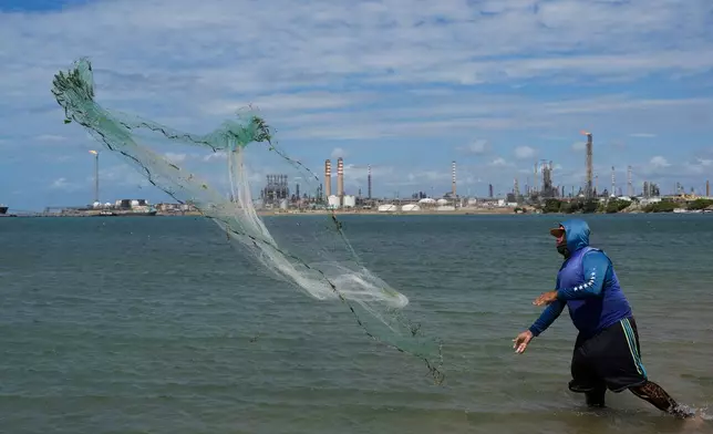 A fisherman throws his net with the Cardon refinery in the background in Punta Cardon, Venezuela, Wednesday, Jan. 14, 2026. (AP Photo/Matias Delacroix)