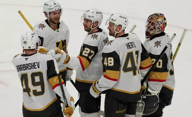 Vegas Golden Knights defenseman Shea Theodore, middle, is congratulated by teammates after scoring an empty net goal during the third period of an NHL hockey game against the San Jose Sharks in San Jose, Calif., Sunday, Jan. 11, 2026. (AP Photo/Jeff Chiu)