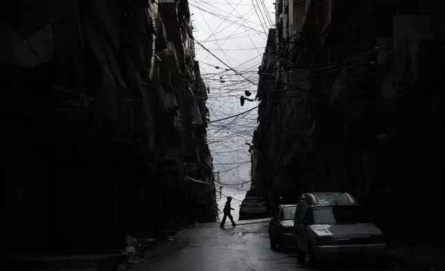 A man crosses a street in the predominantly Kurdish Sheikh Maqsoud neighborhood after days of fighting between government forces and Kurdish fighters in the northern city of Aleppo, Syria, Tuesday, Jan. 13, 2026. (AP Photo/Ghaith Alsayed)