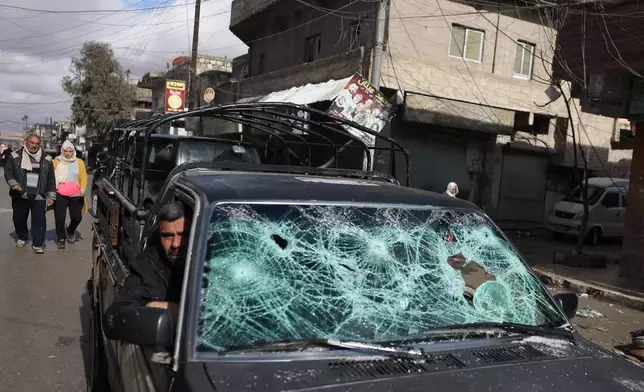 A man rides a damaged car, as displaced residents return to the Sheikh Maqsoud neighborhood after days of fighting between government forces and Kurdish fighters in the northern city of Aleppo, Syria, Tuesday, Jan. 13, 2026. (AP Photo/Omar Albam)