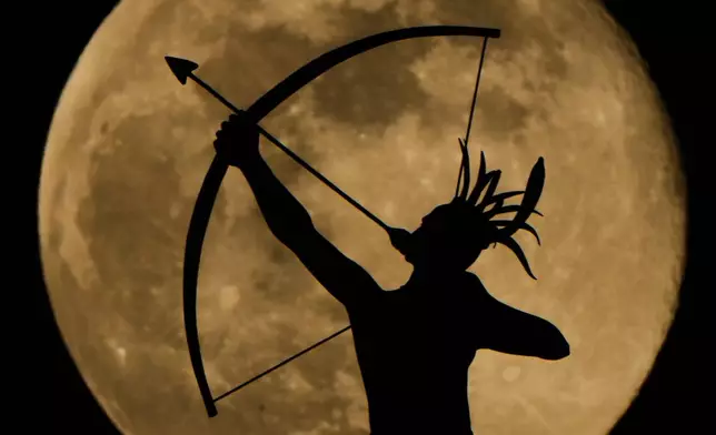 The full moon rises behind the statue, "Ad Astra," atop the Kansas Statehouse, Saturday, Jan. 3, 2026, in Topeka, Kan. (AP Photo/Charlie Riedel)