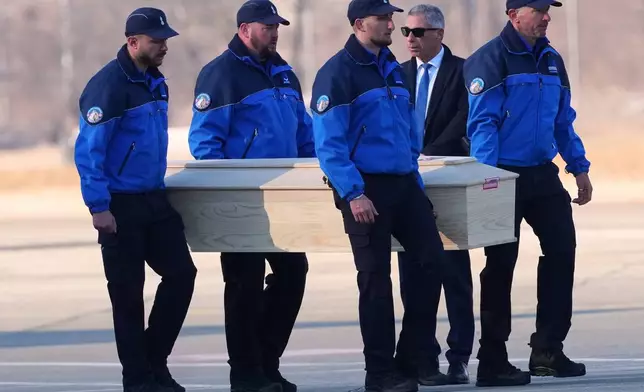 Police officers carry a coffin with a body of one of six Italians at the Military Airport in Sion, Swiss Alps, Switzerland, Monday, Jan. 5, 2026, following a devastating fire left dead and injured in a bar in Crans-Montana during the New Year's celebrations. (AP Photo/Antonio Calanni)