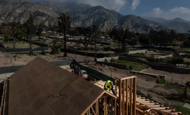 A construction worker hammers on the roof of a home being rebuilt, Wednesday, Dec. 3, 2025, in Altadena, Calif., months after the Eaton Fire. (AP Photo/Jae C. Hong)