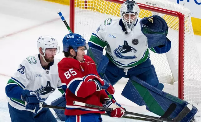 Vancouver Canucks goaltender Nikita Tolopilo (60) watches the puck in front of Montreal Canadiens' Alexandre Texier (85) as Canucks' Marcus Pettersson (29) defends during second-period NHL hockey game action in Montreal, Monday, Jan. 12, 2026. (Christinne Muschi/The Canadian Press via AP)