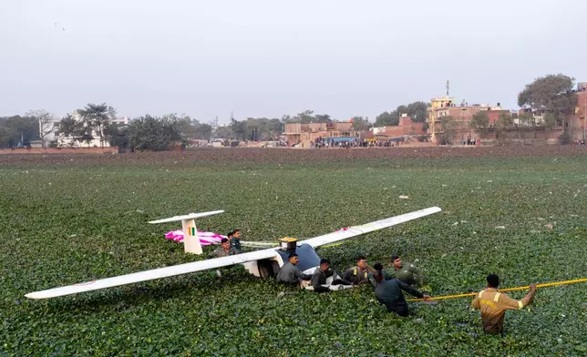 Air Force personnel with the State Disaster Response Force remove the wreckage of a microlight training aircraft after it crashed during a training exercise into a foliage-covered pond in Prayagraj, India, Wednesday, Jan. 21, 2026. (AP Photo/Rajesh Kumar Singh)