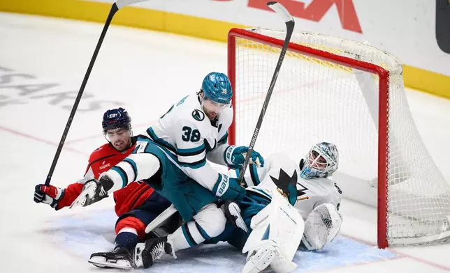 Washington Capitals center Hendrix Lapierre (29) collides with San Jose Sharks defenseman Mario Ferraro (38) and goaltender Alex Nedeljkovic (33) during the third period of an NHL hockey game, Thursday, Jan. 15, 2026, in Washington. (AP Photo/Nick Wass)