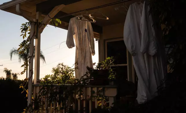 Protective suits hang outside a home that survived the Eaton Fire, Dec. 2, 2025, in Altadena, Calif., as cleaning crews remove fire debris from the property. (AP Photo/Jae C. Hong)