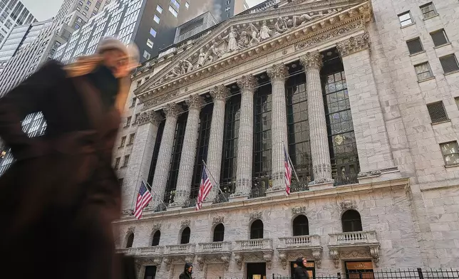 Morning commuters pass the New York Stock Exchange, Tuesday, Jan. 20, 2026. (AP Photo/Richard Drew)