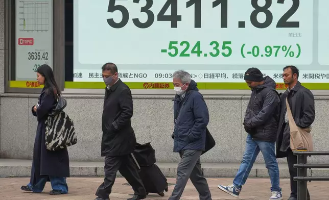 People walk in front of an electronic stock board showing Japan's Nikkei index at a securities firm Monday, Jan. 19, 2026, in Tokyo. (AP Photo/Eugene Hoshiko)
