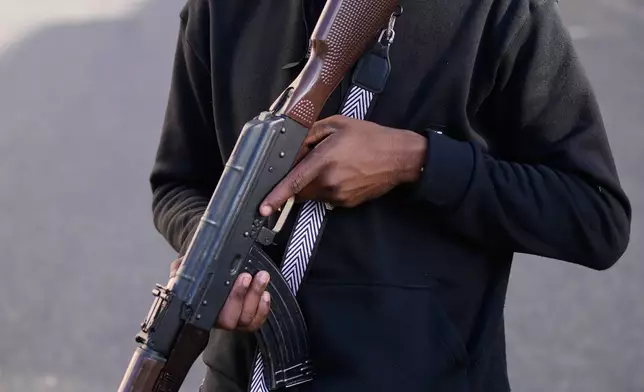 FILE - An armed, pro-government civilian stands near shoppers lining up outside a supermarket in Caracas, Venezuela, Jan. 4, 2026. (AP Photo/Ariana Cubillos, File)