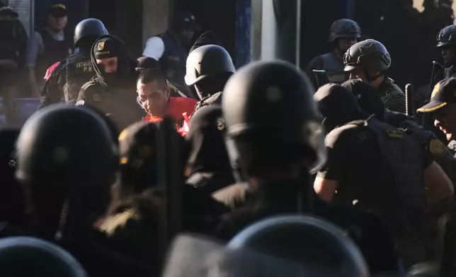 Security forces escort an inmate after entering the Renovation maximum-security prison to free guards taken hostage and retake control of the facility, which houses gang leaders, in Escuintla, Guatemala, Sunday, Jan. 18, 2026. (AP Photo/Moises Castillo)