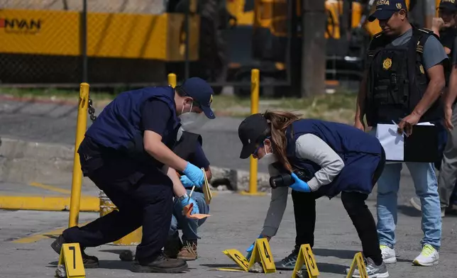 Forensic investigators place evidence markers at the scene where police officers were killed in attacks reported after security forces retook control of a prison that houses gang leaders, in Villanueva, outskirts of Guatemala City, Sunday, Jan. 18, 2026. (AP Photo/Moises Castillo)