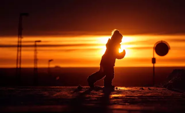 A boy runs across a street at a sunset in Nuuk, Greenland, on Wednesday, Jan. 21, 2026. (AP Photo/Evgeniy Maloletka)