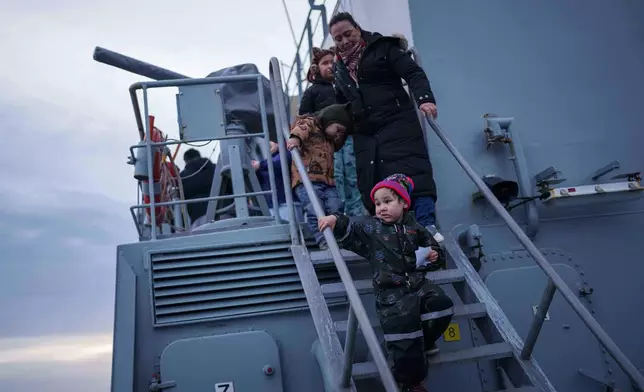A mother with her children walk on stairs of a naval vessel during a public day in Nuuk, Greenland, Saturday, Jan. 24, 2026. (AP Photo/Evgeniy Maloletka)