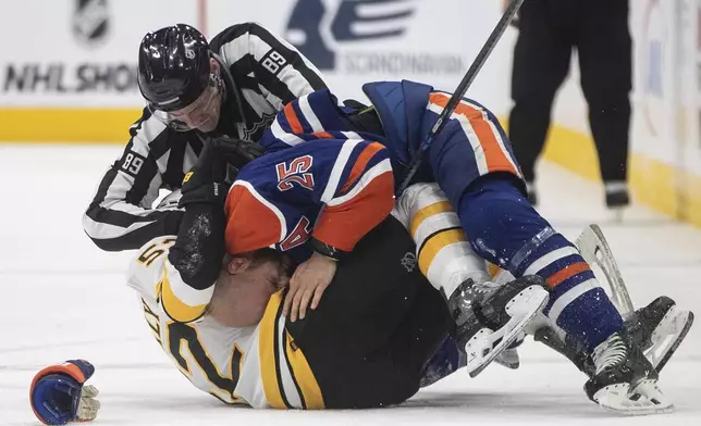 Boston Bruins' Sean Kuraly (52) and Edmonton Oilers' Darnell Nurse (25) fight during the third period of an NHL hockey game in Edmonton, Alberta, on Wednesday, Dec. 31, 2025. (Jason Franson/The Canadian Press via AP)