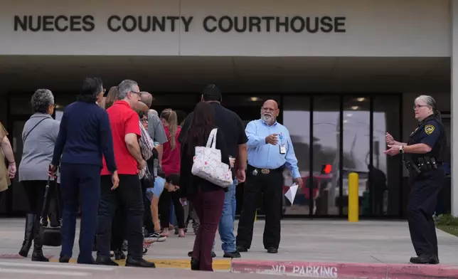 Officials monitor a line outside the Nueces County Courthouse in Corpus Christi, Texas, where jury selection begins for the State of Texas v. Adrian Gonzales, a former police officer for schools in Uvalde, Monday, Jan. 5, 2026. (AP Photo/Eric Gay)