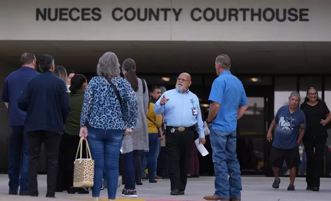 Officials monitor a line outside the Nueces County Courthouse in Corpus Christi, Texas, where jury selection begins for the State of Texas v. Adrian Gonzales, a former police officer for schools in Uvalde, Monday, Jan. 5, 2026. (AP Photo/Eric Gay)
