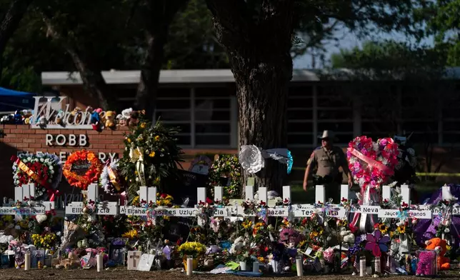 FILE - Flowers and candles are placed around crosses to honor the victims killed in a school shooting, May 28, 2022, outside Robb Elementary School in Uvalde, Texas. (AP Photo/Jae C. Hong, File)