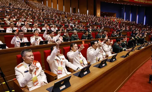 Delegates hold up Communist Party member cards as a vote during a meeting in preparation for the opening of the National Congress in Hanoi, Vietnam, Monday, Jan. 19, 2026. (Bui Cuong Quyet/VNA via AP)