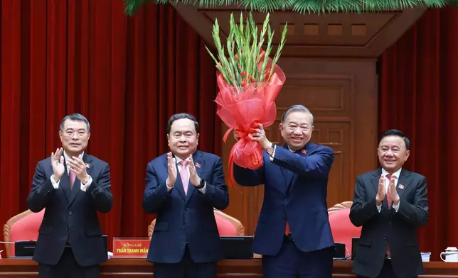 Vietnam's General Secretary of the Communist Party To Lam, second right, holds up a bouquet after being re-elected to the position following a National Congress in Hanoi, Vietnam, Friday, Jan. 23, 2026. (Hoang Thong Nhat/VNA via AP)