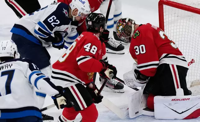 Chicago Blackhawks goaltender Spencer Knight (30) saves a shot by Winnipeg Jets right wing Nino Niederreiter (62) during the first period of an NHL hockey game in Chicago, Monday, Jan. 19, 2026. (AP Photo/Nam Y. Huh)