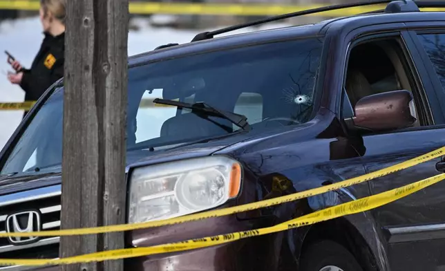 A bullet hole is seen in the windshield as law enforcement officers work at the scene of a shooting involving federal law enforcement agents, Wednesday, Jan. 7, 2026, in Minneapolis. (AP Photo/Tom Baker)