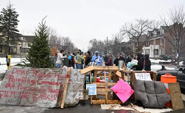 People gather around a makeshift memorial honoring the victim of a fatal shooting involving federal law enforcement agents, near the site of the shooting, Thursday, Jan. 8, 2026, in Minneapolis. (AP Photo/Tom Baker)